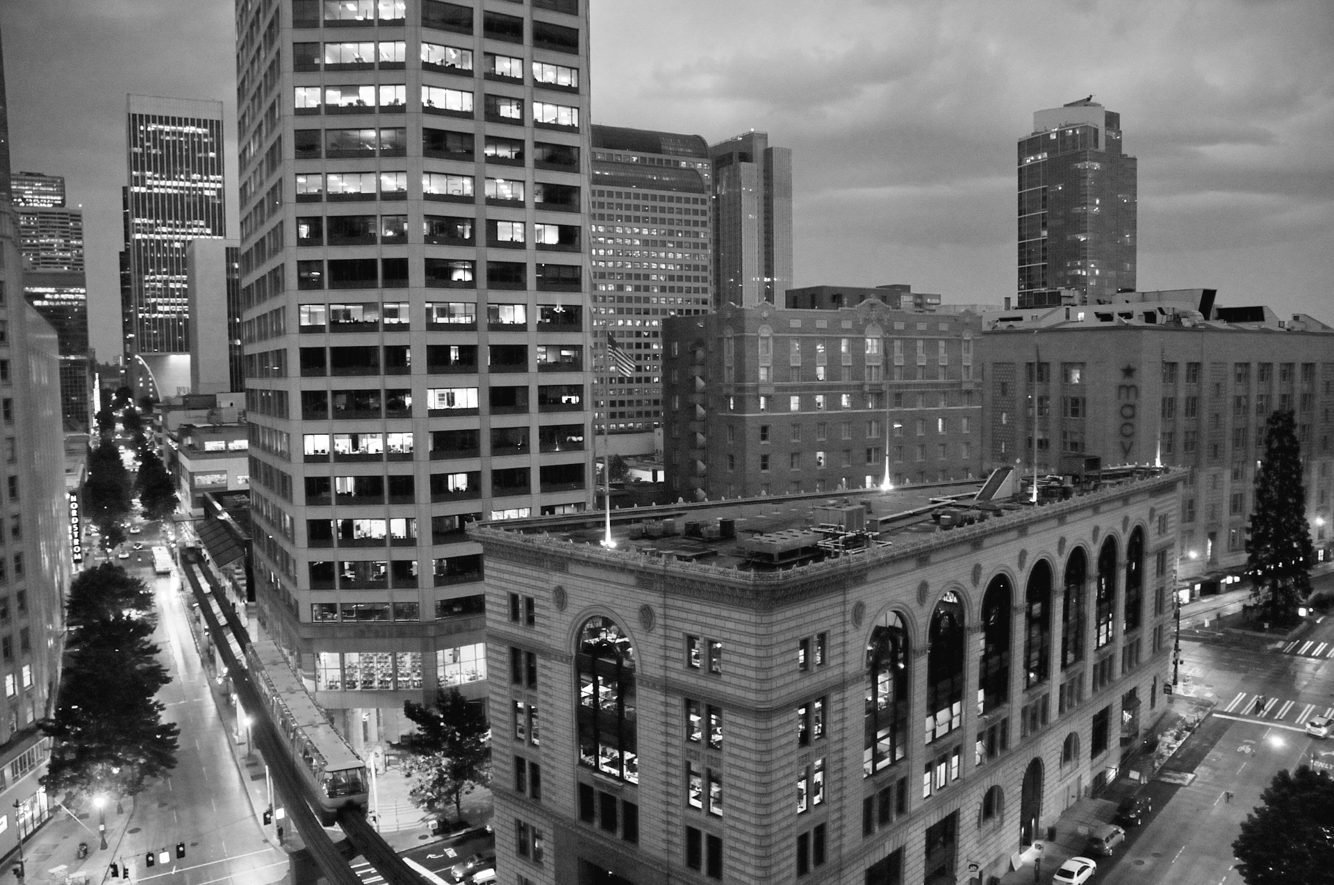 Downtown skyline at dusk with lit office windows above wet streets