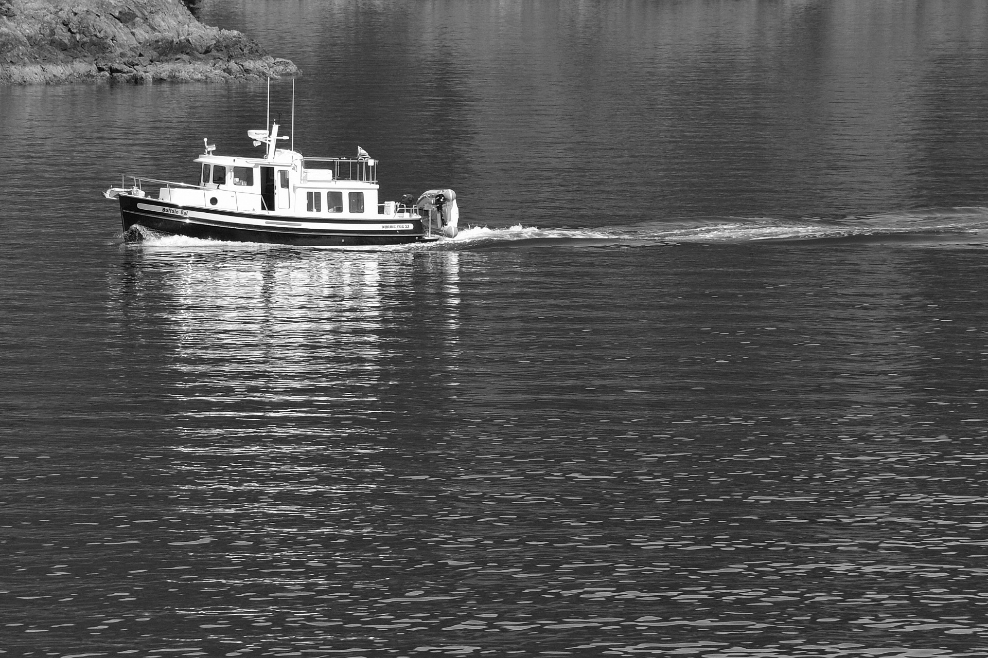 A small working tugboat crossing flat rippled water